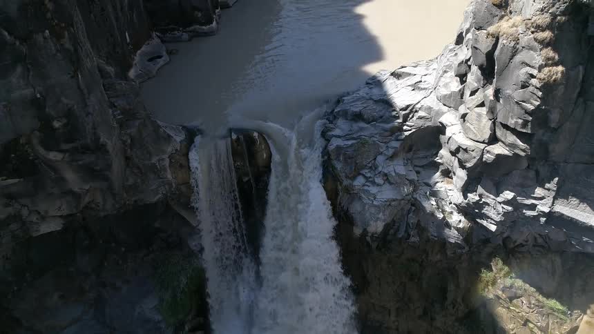 The waterfall pours over the rocks