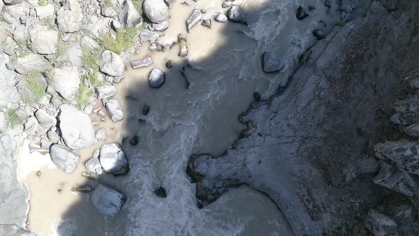 Water flows forcefully along a river through very rocky terrain
