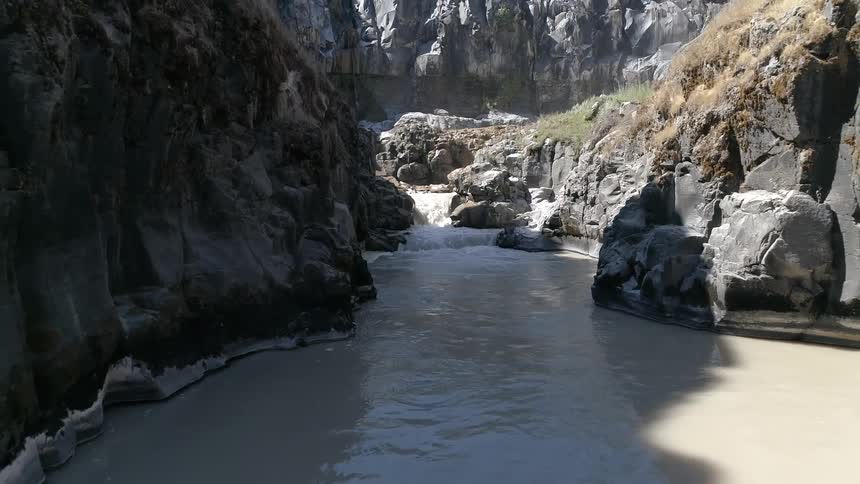 The river sits surrounded by rocks under the bright sun