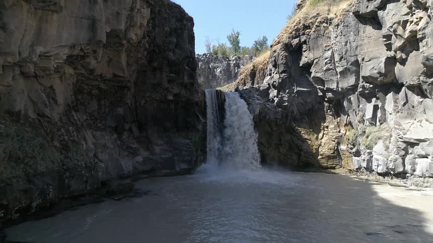 A waterfall crashes in to the muddy waters below