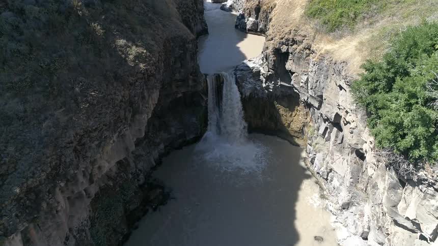 A waterfall crashes in to the muddy waters below