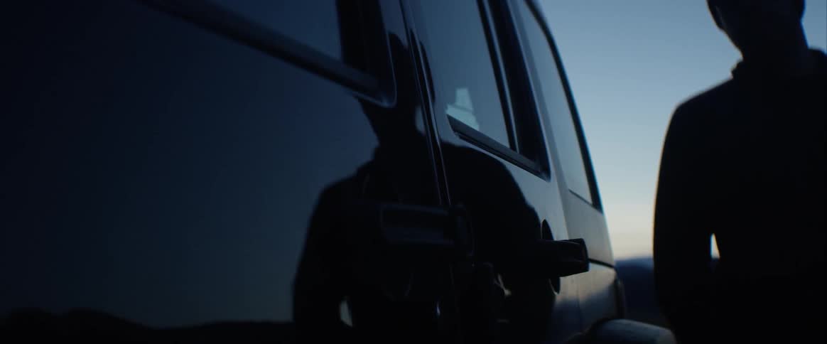 Two men walk towards a vehicle at night and then get in