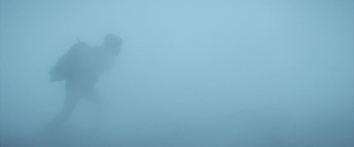 A person with a backpack walking in a blizzard