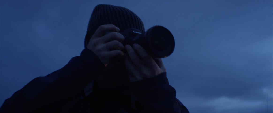 A young man takes pictures outside at night