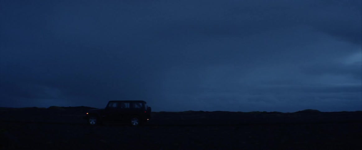 A vehicle drives down a road at night
