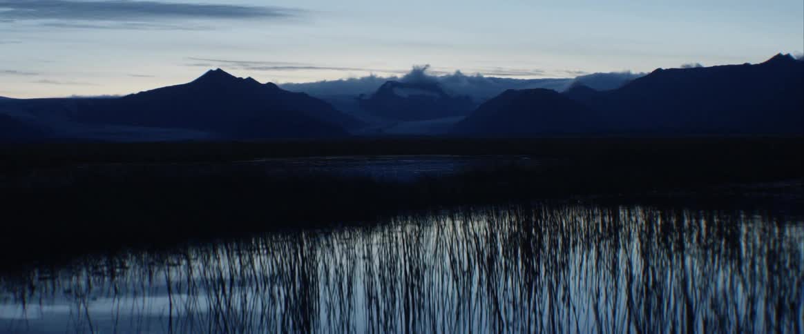 A still lake with mountains looming behind