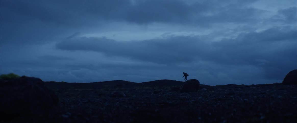 A person walking along a rocky landscape in the evening