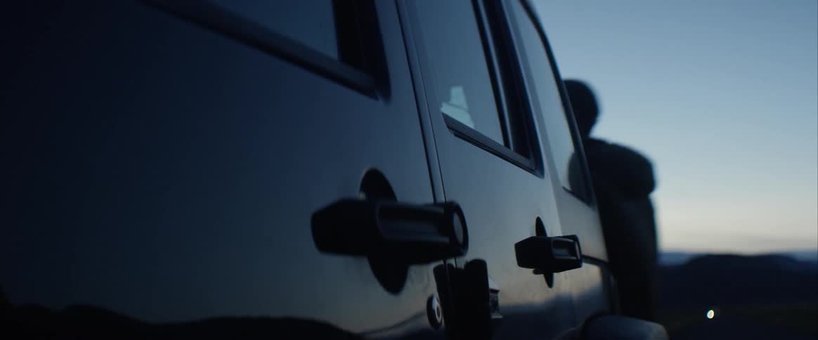 Two people get inside a car parked outside at night