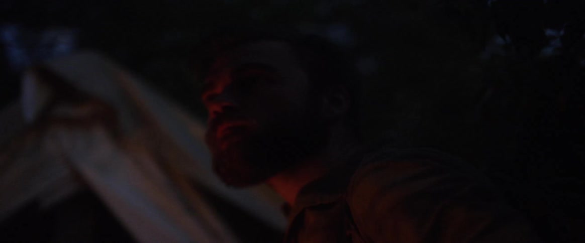 A man working in front of a tent at night