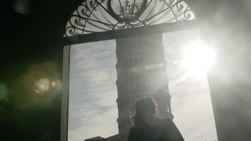 A woman walking outside in front of the leaning tower of pisa
