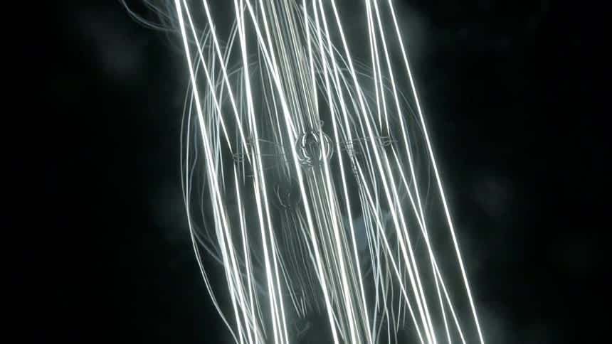 Electrical filaments glow and blur and reflect against black