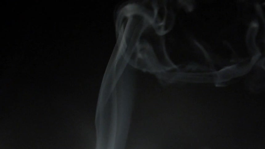 White smoke curls up in the air against a dark background