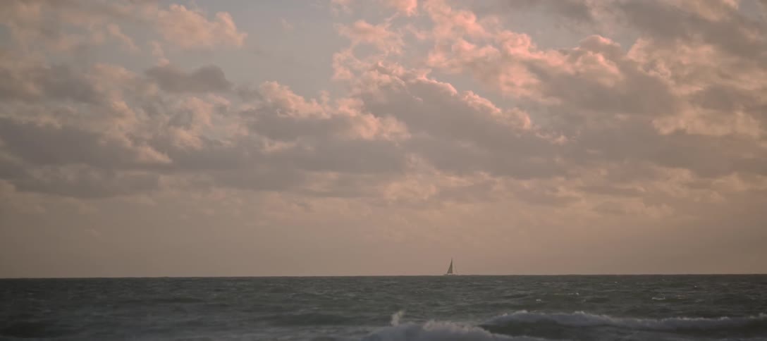 A sailboat crosses over the ocean