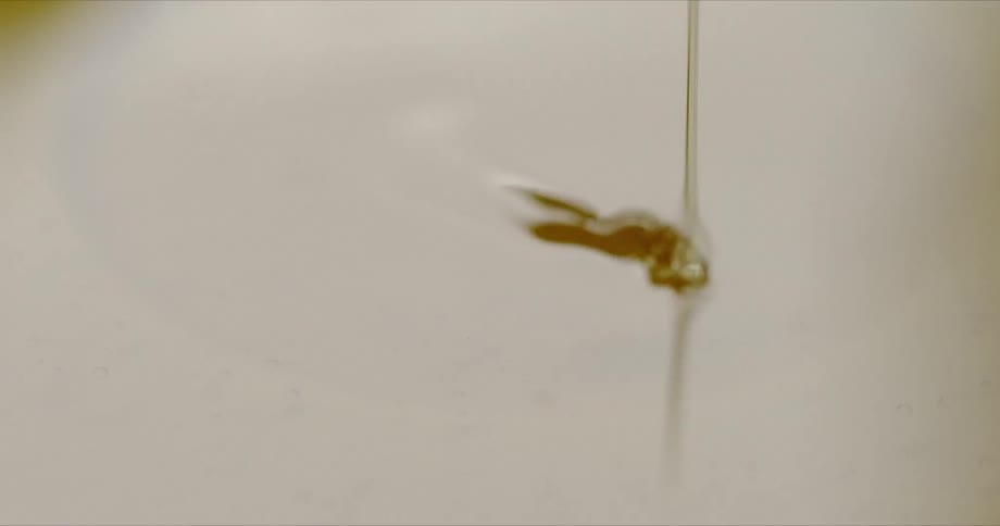 Golden honey is poured then drips