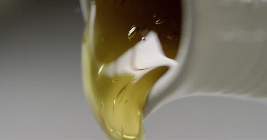 Thick honey pours out of a container
