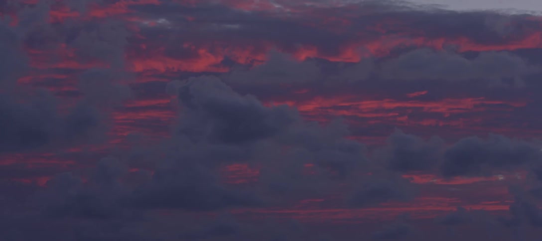 Storm clouds in front of a red sky at night