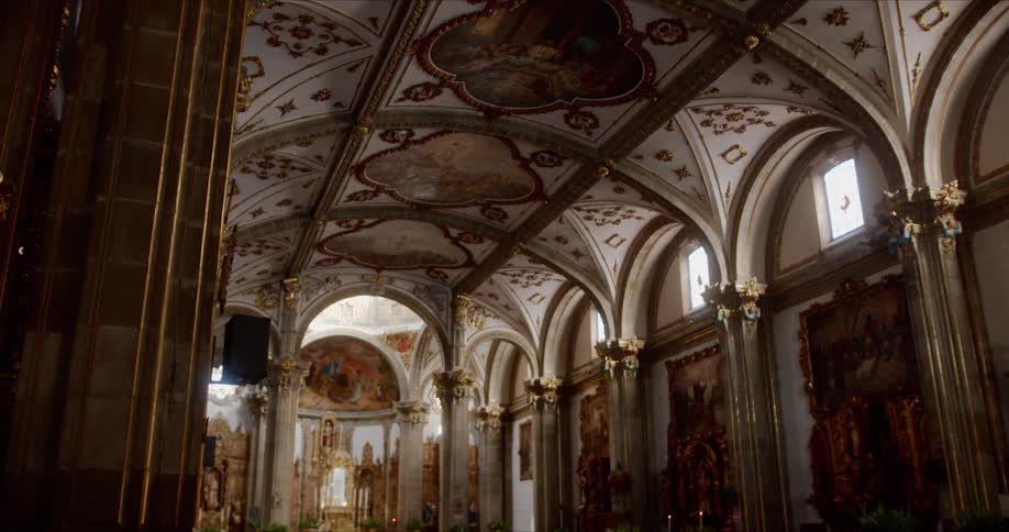 People walk through church with elaborate painted and carved ceiling
