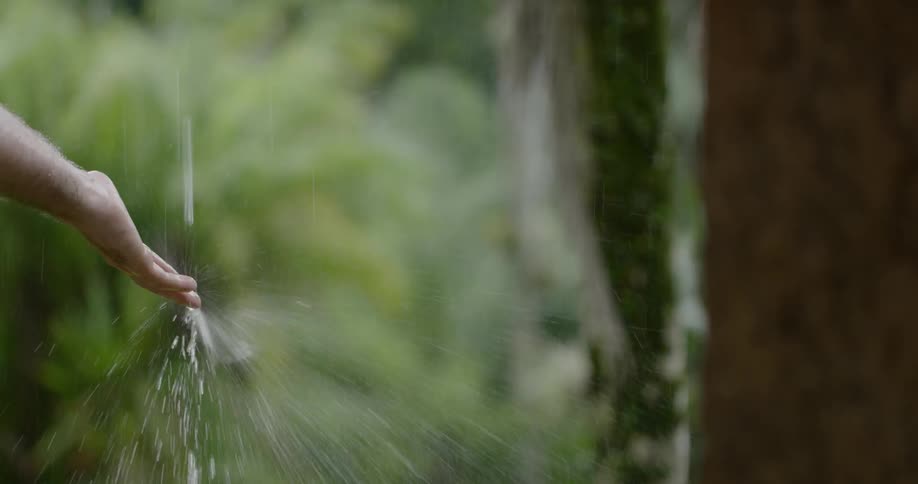 A man holding his hand out to falling water