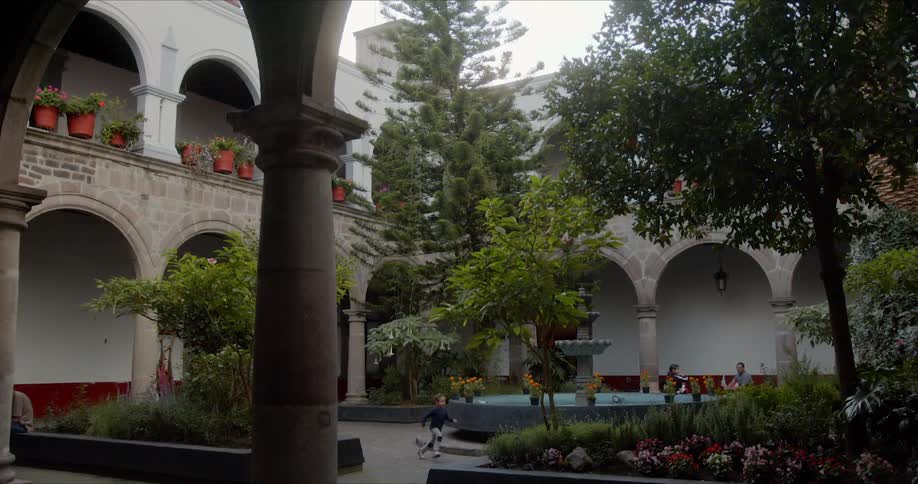 Boy runs around fountain in building courtyard