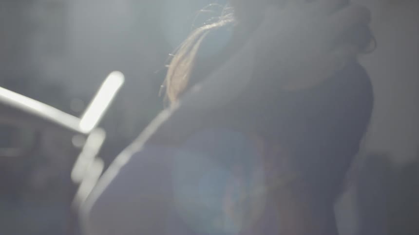 A woman tying her hair while standing in sunlight