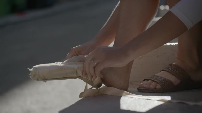 A woman puts on her ballet slippers