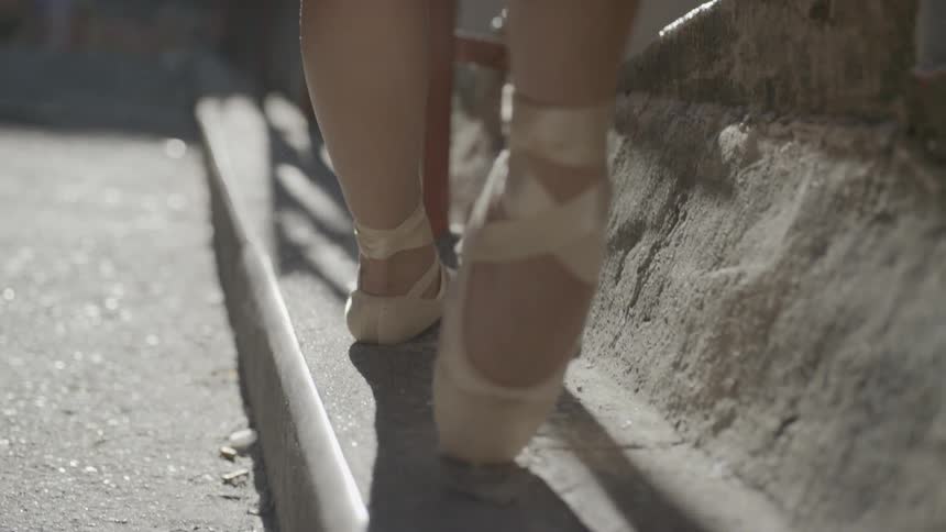 A ballet dancer practices pointe on an outdoor staircase