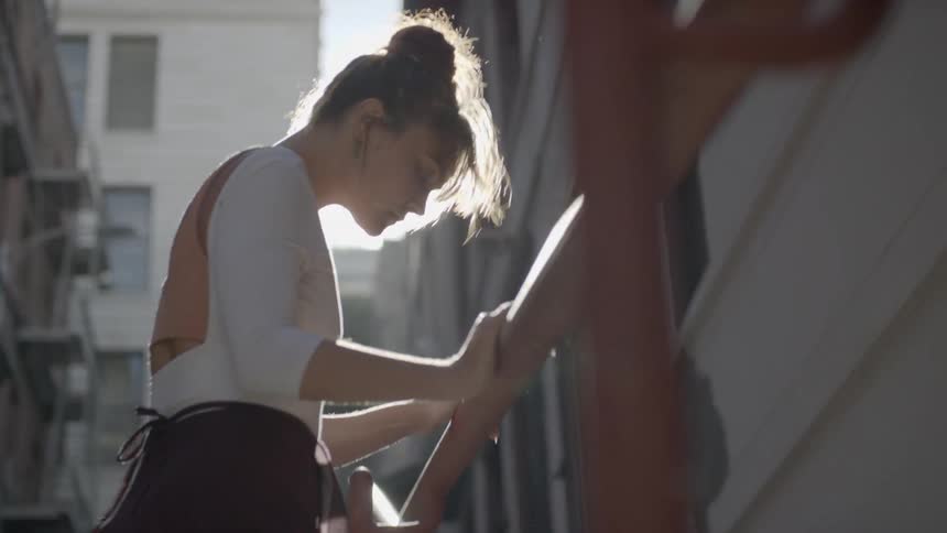 Ballerina holding a handrail and wearing pointe shoe stands on tip toes in the street