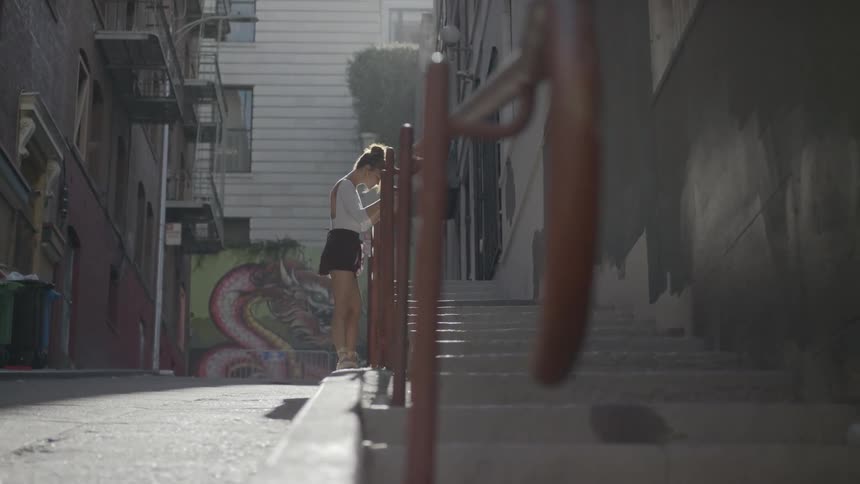 A woman outside in an alley practicing her ballet
