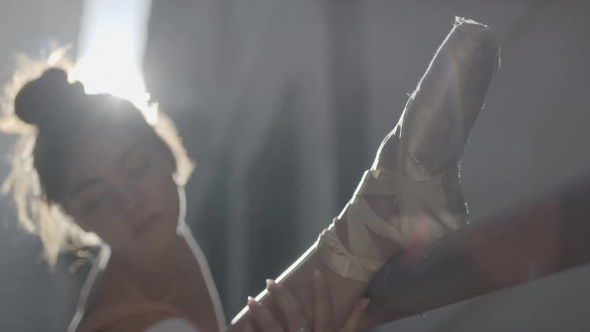 A ballerina doing stretches outdoors during the day