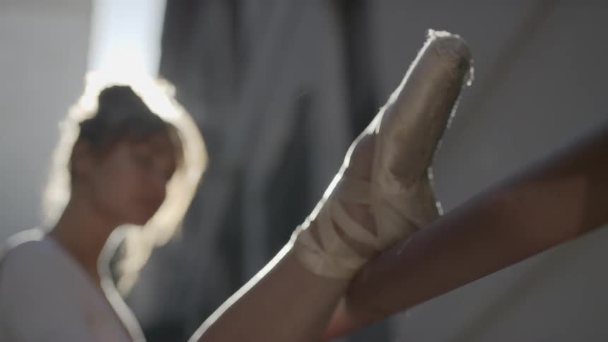 A ballerina outside putting her foot on a ballet barre