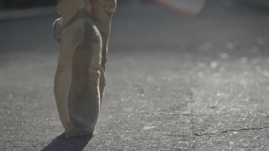 A ballet dancer gets on her toes while dancing in an alley