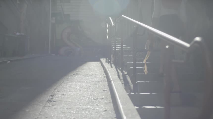 A woman walks up steps outdoors while carrying ballet slippers