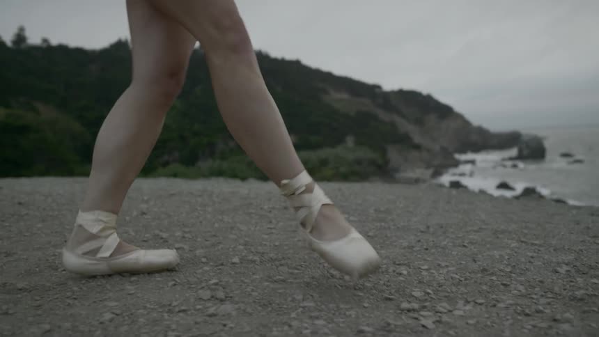 A ballerina twirls on a beach