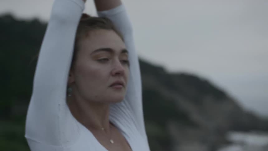 Ballerina dances on the hill next to the sea on a cloudy day
