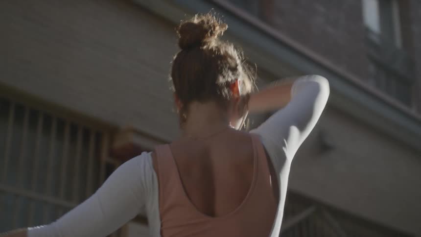 A woman dancing outdoors in a city during the day