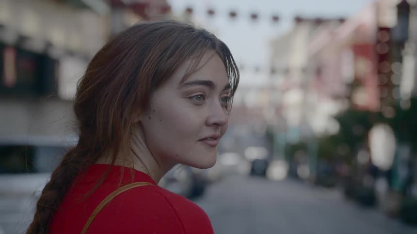A woman standing outside in the streets staring off into the distance