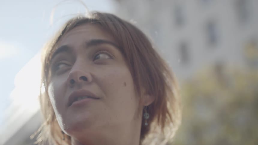 A young woman stands outside and looks around