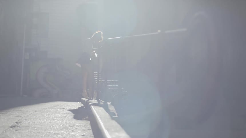 Woman stands on a ledge as a spotlight shines on her