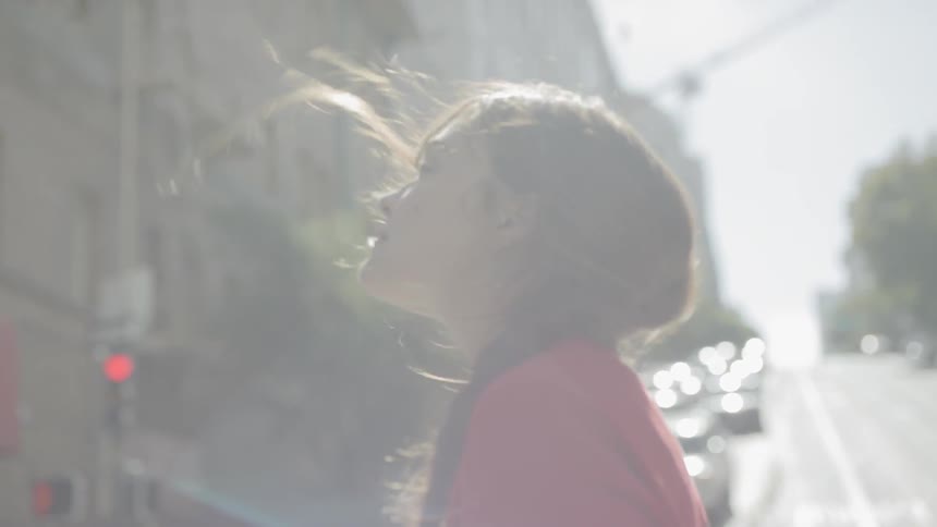 A young woman looks up as she crosses a road with multiple lanes