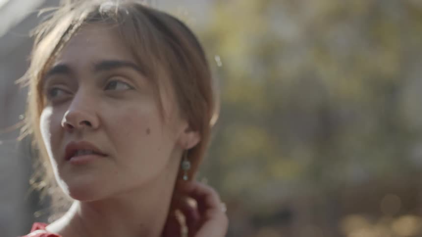 A woman runs her hand through her hair and looks off in to the distance