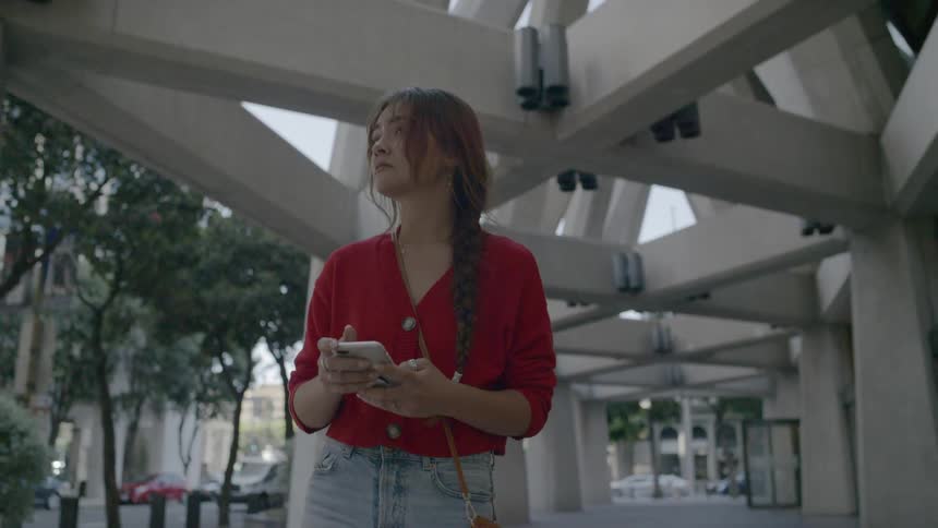 A woman walks down the sidewalk while looking at her phone