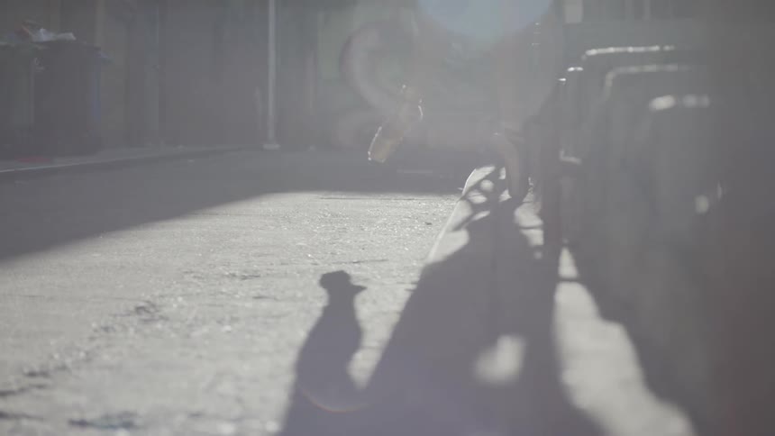 A female ballerina stands on her toes in an urban setting while outdoors in the sunlight