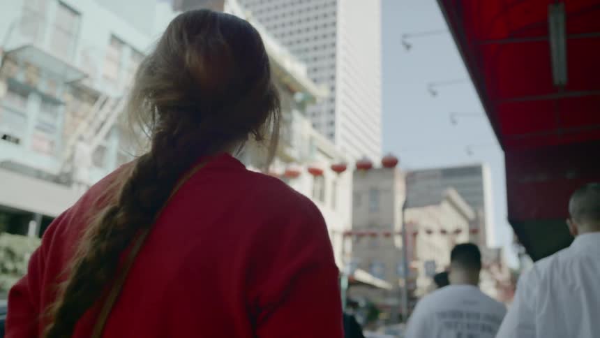 Blonde woman wearing a red sweater walks down the street in the city