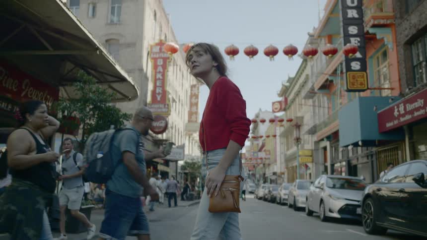 A crowd of people cross the street and walk along the sidewalk in chinatown