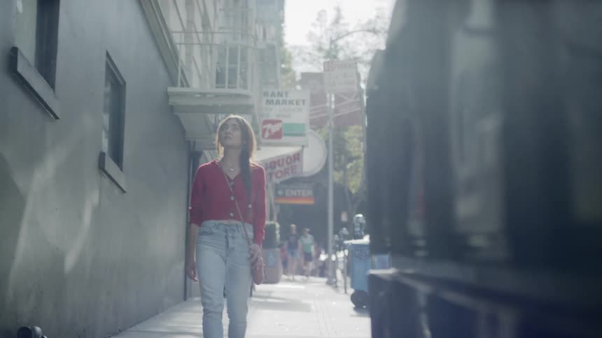 Woman walks along sidewalk looking around