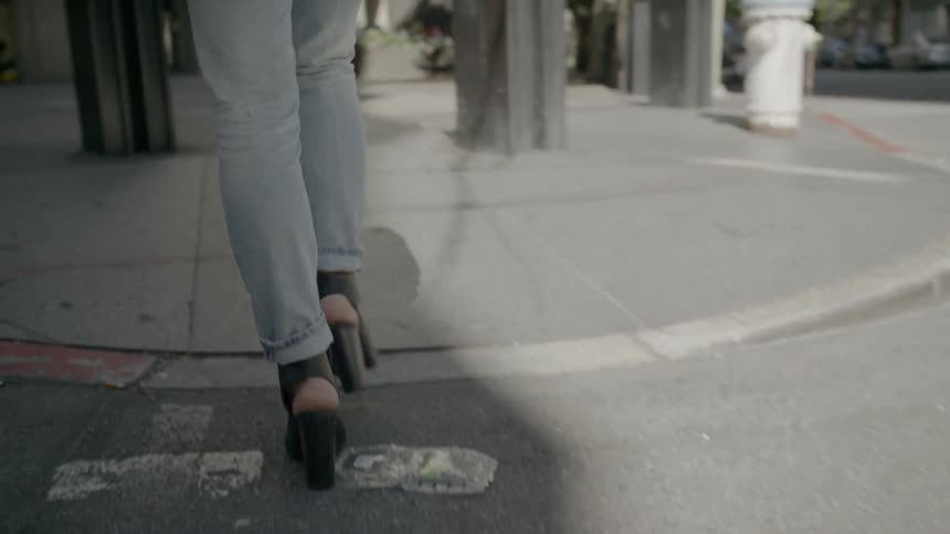A woman crossing the street in a city with buildings in the background