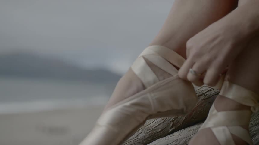 A ballerina ties her slippers on outside