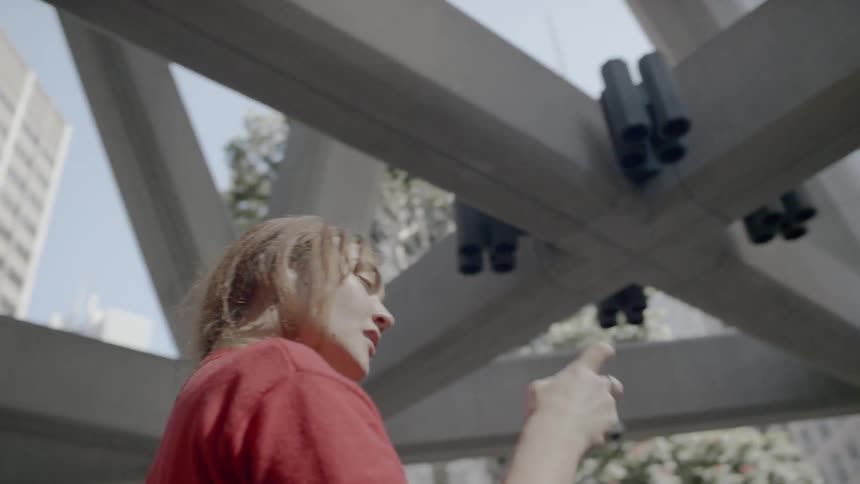 A woman in a red sweater taking photographs of architecture in a city with her smartphone