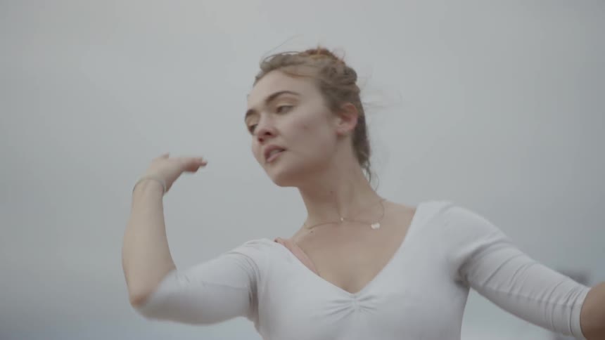 A ballet dancer dances outdoors near a body of water