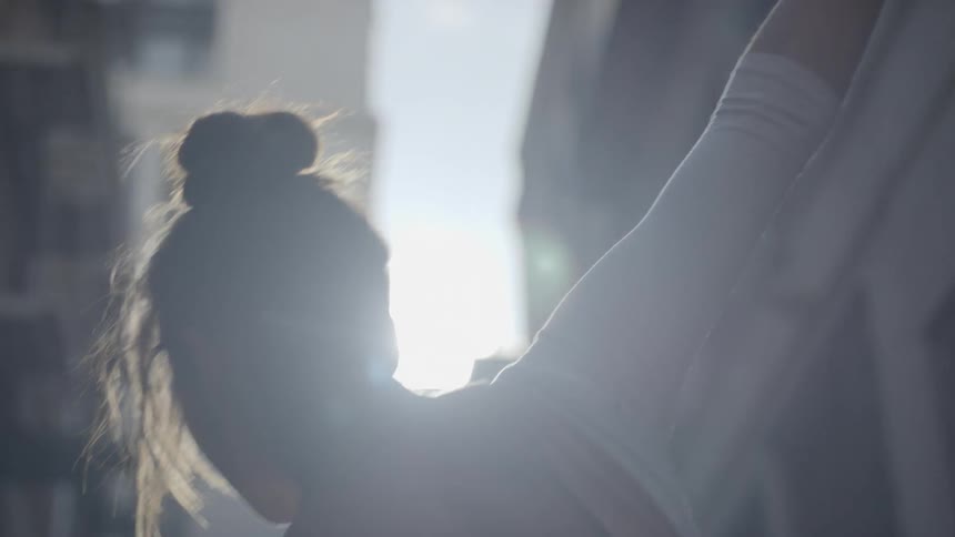 A woman dances on a city street under a bright sun